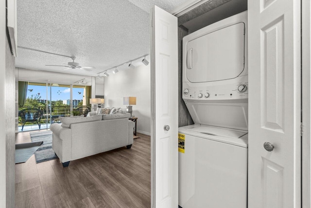 clothes washing area with laundry area, ceiling fan, dark wood-type flooring, a textured ceiling, and stacked washer / dryer