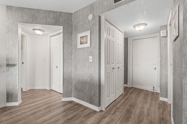 corridor with hardwood / wood-style flooring and a textured ceiling