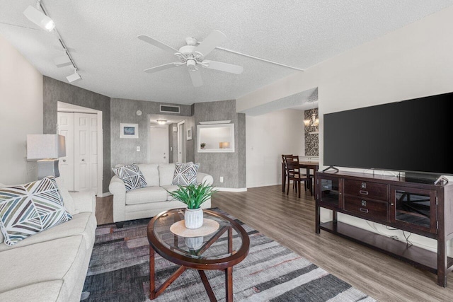 living room with hardwood / wood-style flooring, ceiling fan with notable chandelier, a textured ceiling, and track lighting