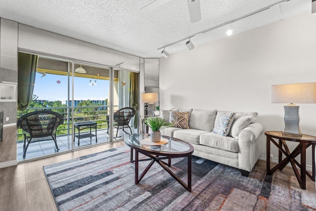 living room featuring ceiling fan, wood-type flooring, and a textured ceiling