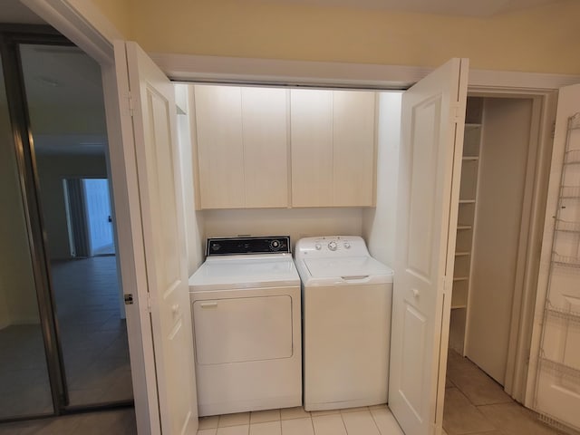 clothes washing area featuring cabinets, washer and dryer, and light tile patterned floors