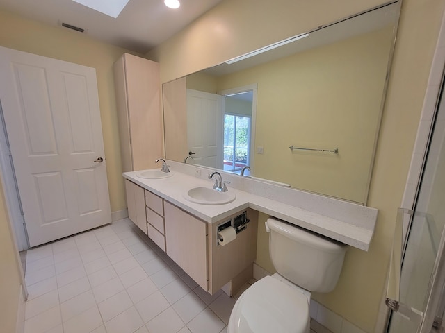 bathroom with vanity, toilet, a skylight, and tile patterned flooring