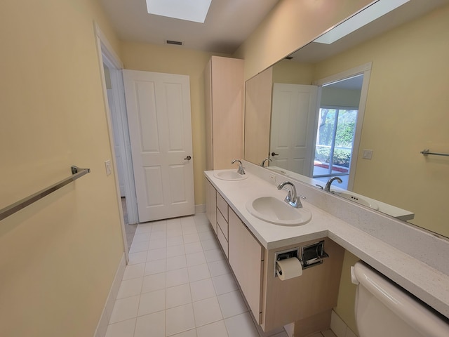 bathroom featuring vanity, tile patterned flooring, a skylight, and toilet