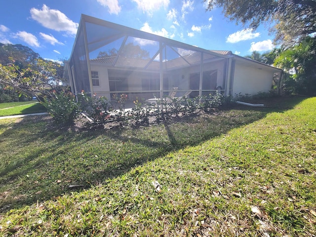 back of property featuring a lanai and a lawn