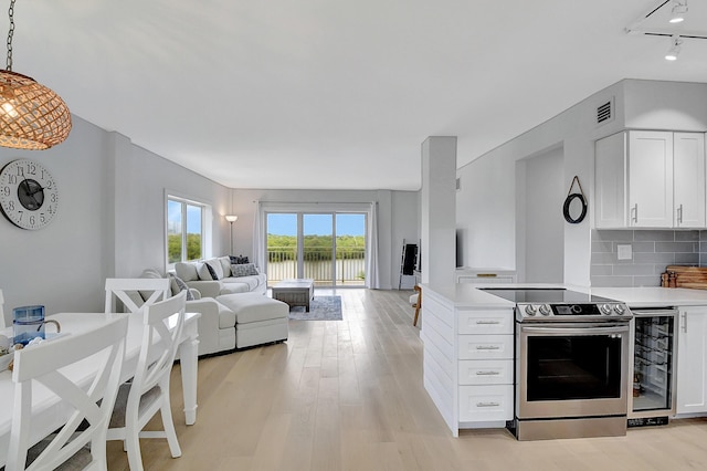 kitchen with open floor plan, light countertops, stainless steel electric range oven, and white cabinetry