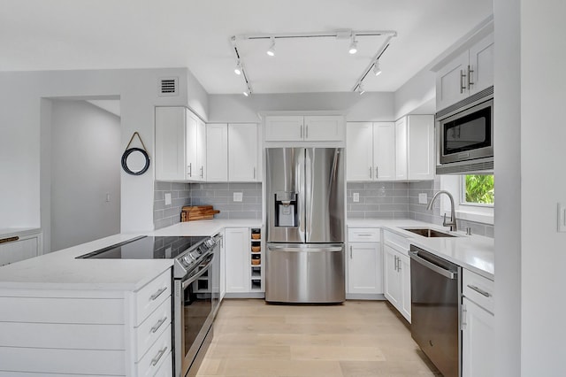 kitchen featuring sink, white cabinetry, light hardwood / wood-style flooring, appliances with stainless steel finishes, and kitchen peninsula