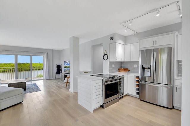 kitchen featuring open floor plan, a water view, a peninsula, stainless steel appliances, and light countertops