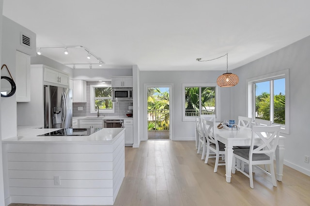 kitchen featuring hanging light fixtures, appliances with stainless steel finishes, sink, and white cabinets