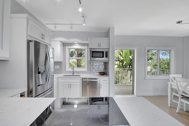 kitchen with white cabinetry, sink, stainless steel appliances, and a healthy amount of sunlight