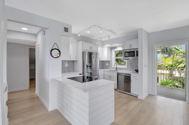 kitchen featuring stainless steel appliances, light countertops, white cabinets, and a peninsula