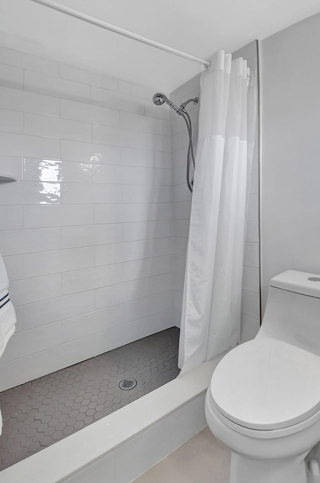 full bath with toilet, a shower stall, and tile patterned floors