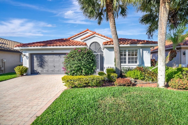 mediterranean / spanish-style house with a garage and a front lawn