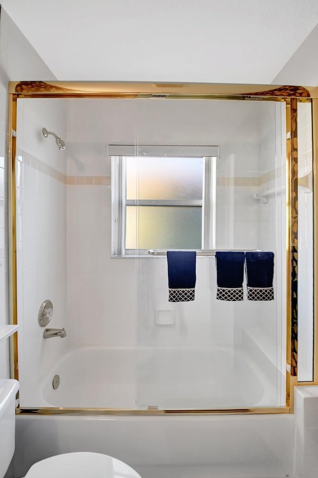 bathroom with toilet and combined bath / shower with glass door