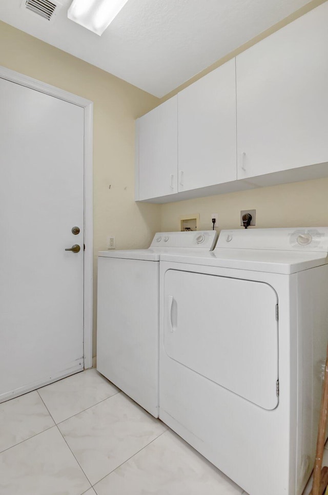 clothes washing area with cabinets and washing machine and clothes dryer