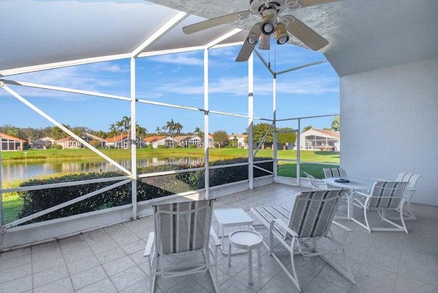 view of patio with ceiling fan, glass enclosure, and a water view