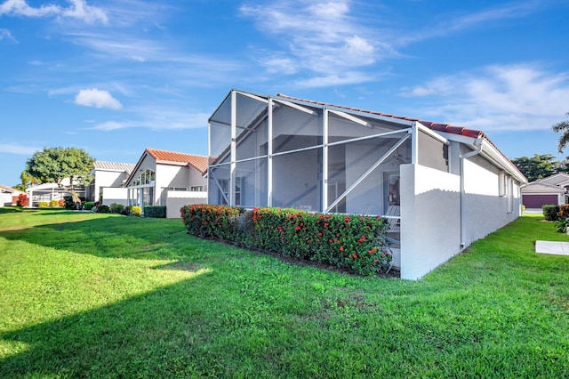 view of property exterior with a yard and glass enclosure