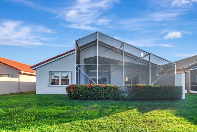 rear view of property featuring ceiling fan, a yard, and a lanai