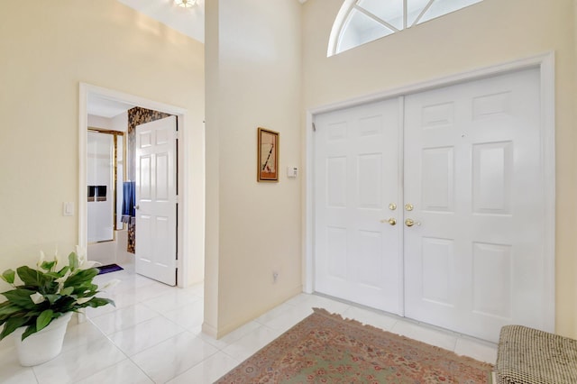 foyer entrance with light tile patterned flooring and a high ceiling