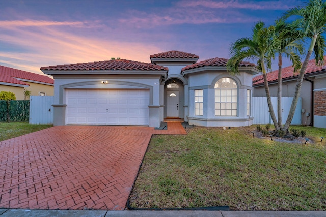 mediterranean / spanish-style house with a garage and a yard