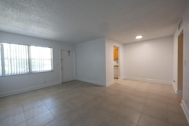 unfurnished room featuring a textured ceiling and light tile patterned floors