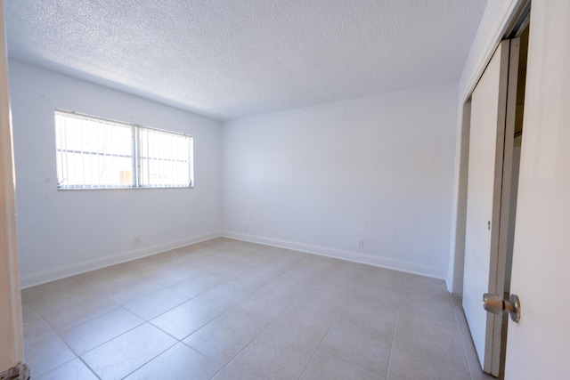 tiled empty room with a textured ceiling