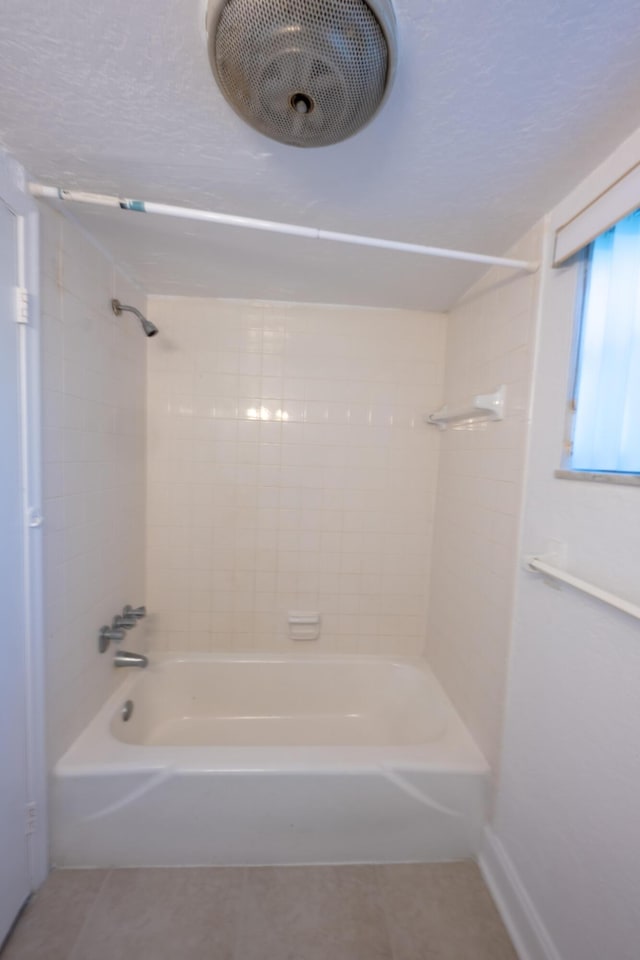 bathroom with tiled shower / bath and tile patterned flooring