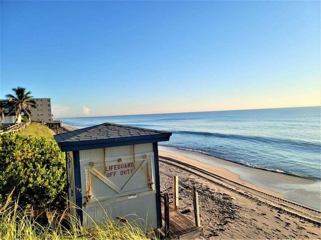 surrounding community with a water view and a beach view