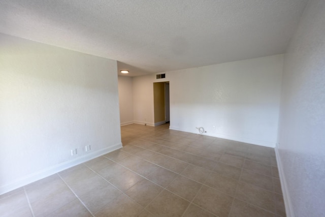 unfurnished room with a textured ceiling and light tile patterned flooring