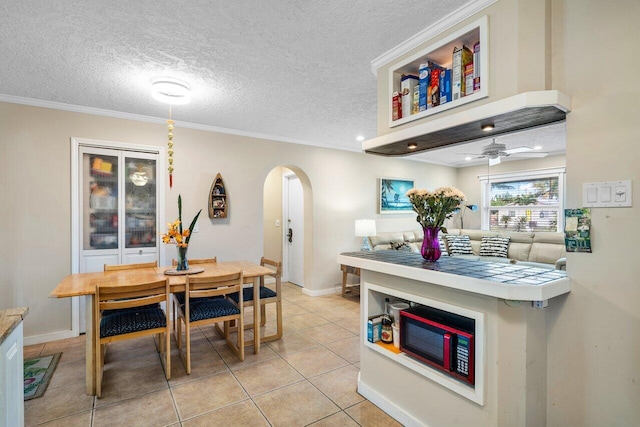 interior space with crown molding, ceiling fan, light tile patterned flooring, and a textured ceiling