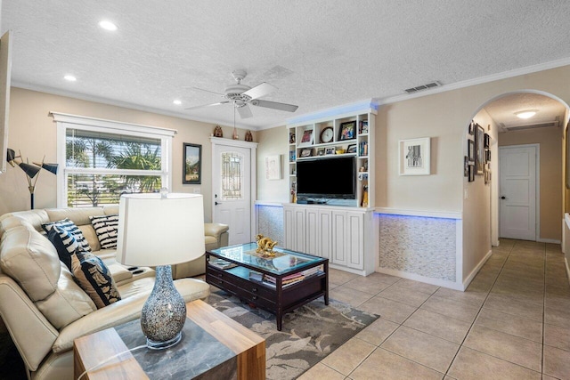 living room featuring crown molding, light tile patterned floors, ceiling fan, and a textured ceiling