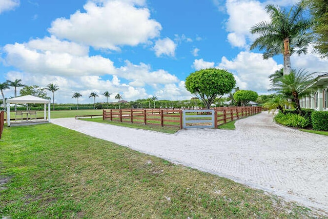 view of home's community with a gazebo, a yard, a rural view, and fence