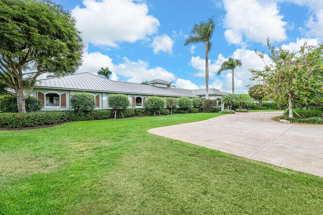 view of front of property featuring metal roof, a front lawn, concrete driveway, and a standing seam roof