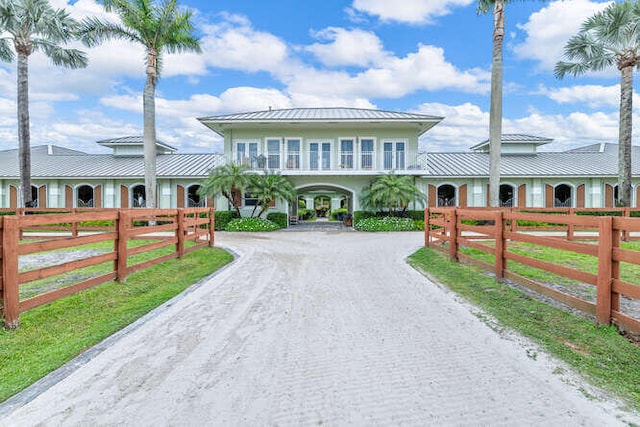 view of front of home featuring gravel driveway, a standing seam roof, and a fenced front yard