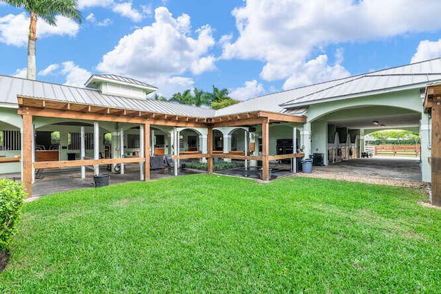 rear view of house with a standing seam roof, metal roof, an outbuilding, and an exterior structure