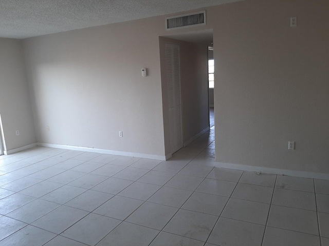 spare room featuring a textured ceiling and light tile patterned floors