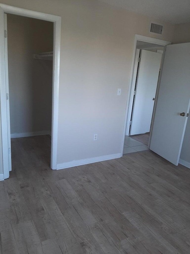 unfurnished bedroom with a walk in closet, a closet, and light hardwood / wood-style flooring