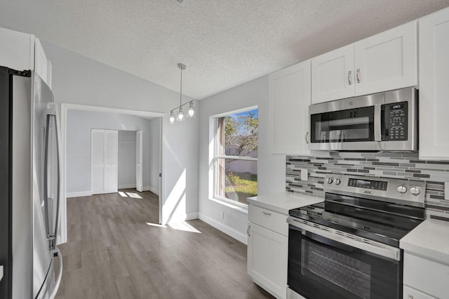 kitchen featuring lofted ceiling, light countertops, tasteful backsplash, and appliances with stainless steel finishes