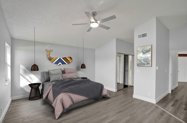 bedroom featuring hardwood / wood-style flooring, lofted ceiling, and a textured ceiling