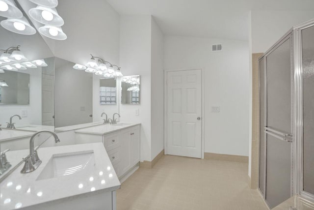 full bath with visible vents, lofted ceiling, two vanities, a stall shower, and a sink