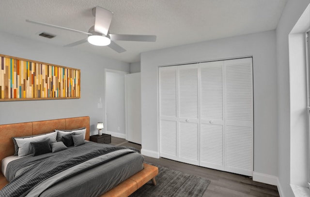 bedroom with dark hardwood / wood-style floors, a textured ceiling, ceiling fan, and a closet