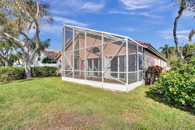 rear view of property with a lanai and a lawn