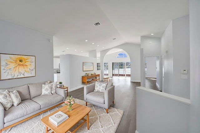 living room with visible vents, wood finished floors, arched walkways, baseboards, and vaulted ceiling