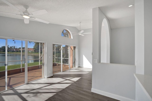 interior space featuring a water view, wood-type flooring, high vaulted ceiling, a textured ceiling, and ceiling fan