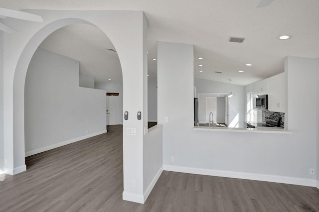 interior space featuring a sink, recessed lighting, baseboards, and wood finished floors