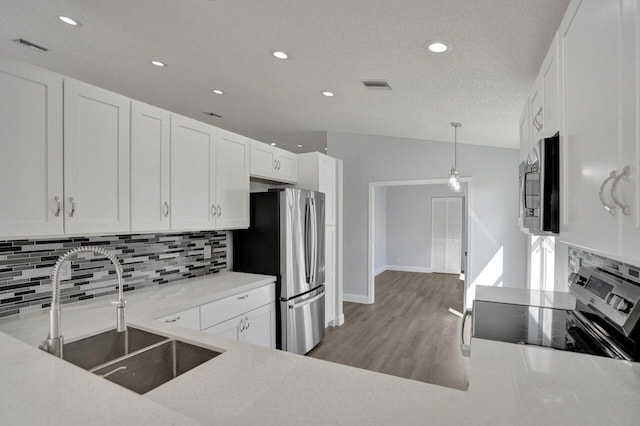 kitchen with sink, appliances with stainless steel finishes, backsplash, white cabinets, and decorative light fixtures