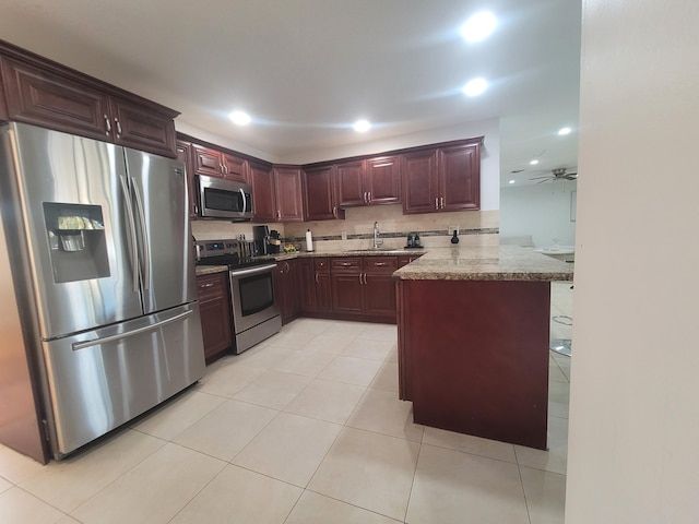 kitchen featuring light stone countertops, appliances with stainless steel finishes, sink, and kitchen peninsula