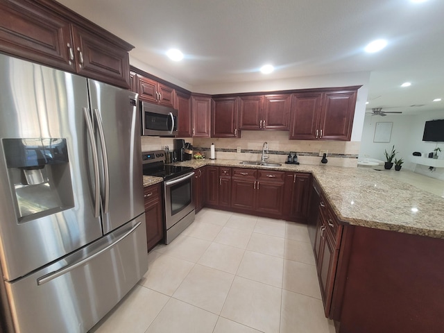 kitchen featuring light stone countertops, appliances with stainless steel finishes, sink, and light tile patterned floors