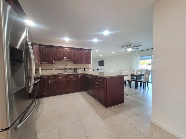 kitchen with light stone countertops, appliances with stainless steel finishes, light tile patterned floors, and kitchen peninsula