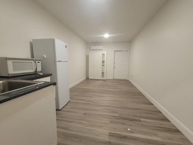 kitchen featuring a wall mounted air conditioner, light hardwood / wood-style floors, and sink