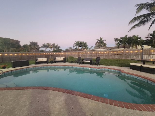 pool at dusk featuring outdoor lounge area and a patio area